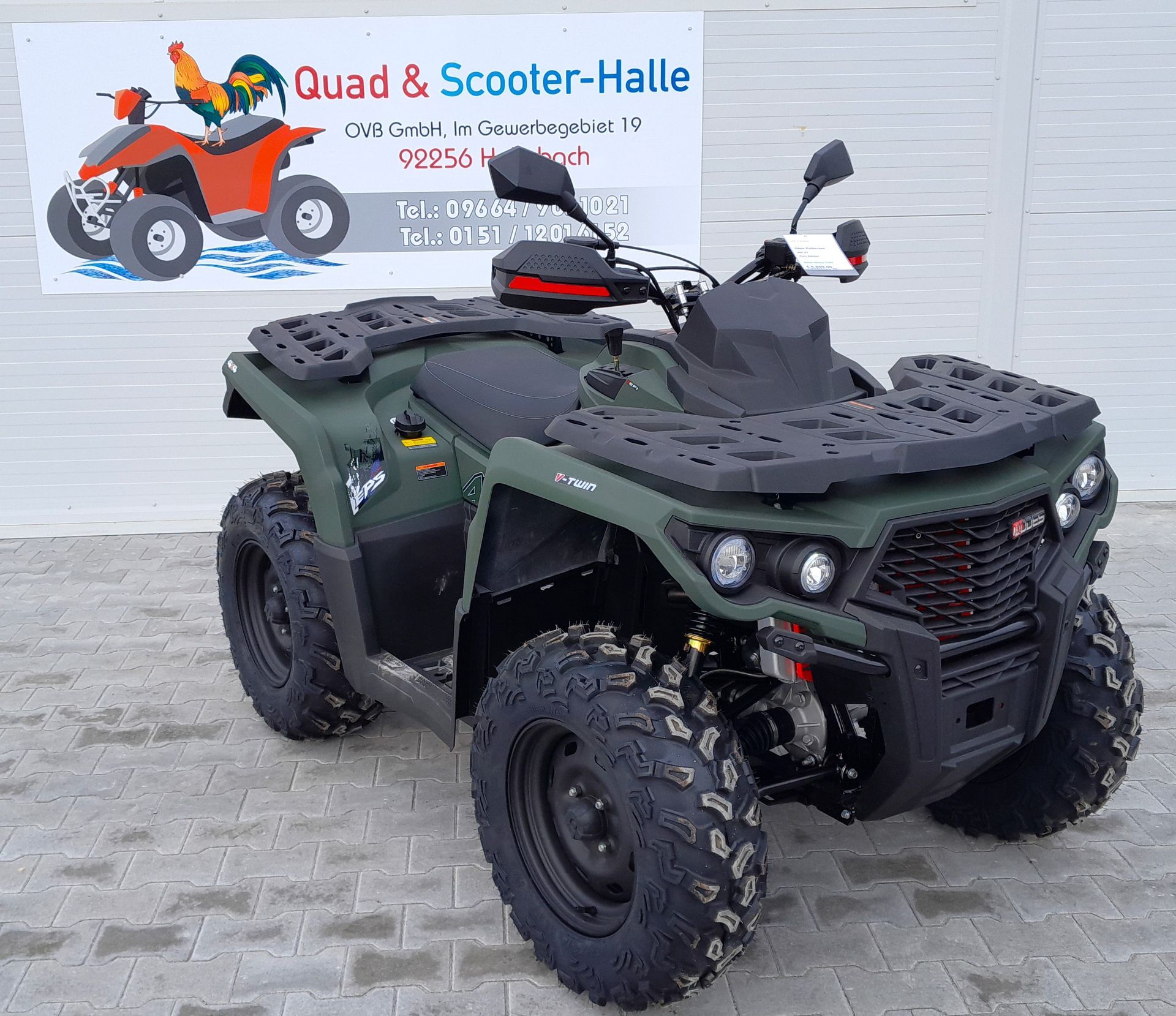 Ein grünes ATV steht vor einem Schild mit der Aufschrift „Quad & Scooter-Halle“