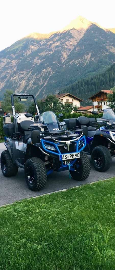Drei Geländefahrzeuge sind nebeneinander vor einem Berg geparkt.
