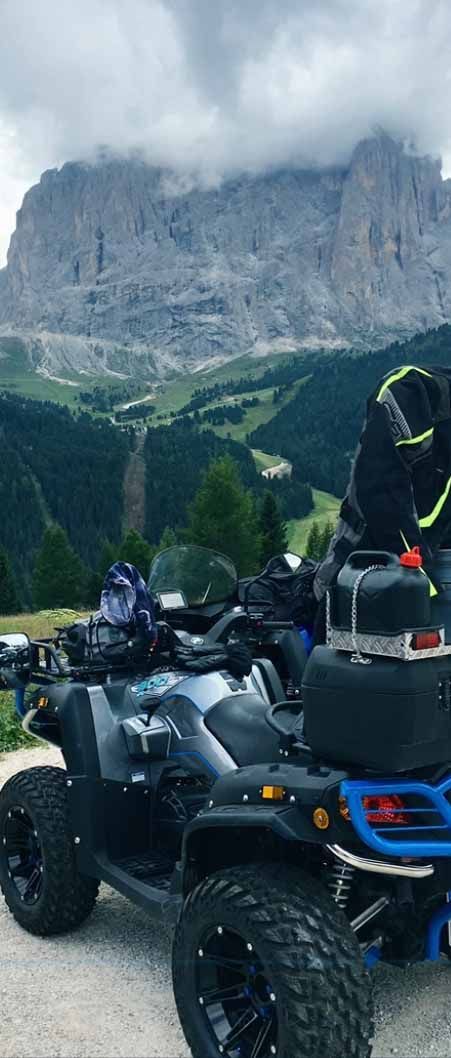 Eine Person fährt mit einem Geländefahrzeug durch die Berge, im Hintergrund ist ein Berg zu sehen.