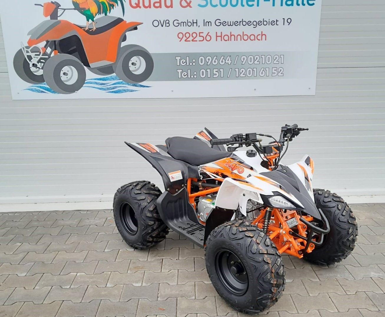 Ein braun-schwarzes Geländefahrzeug ist vor einem Garagentor geparkt.