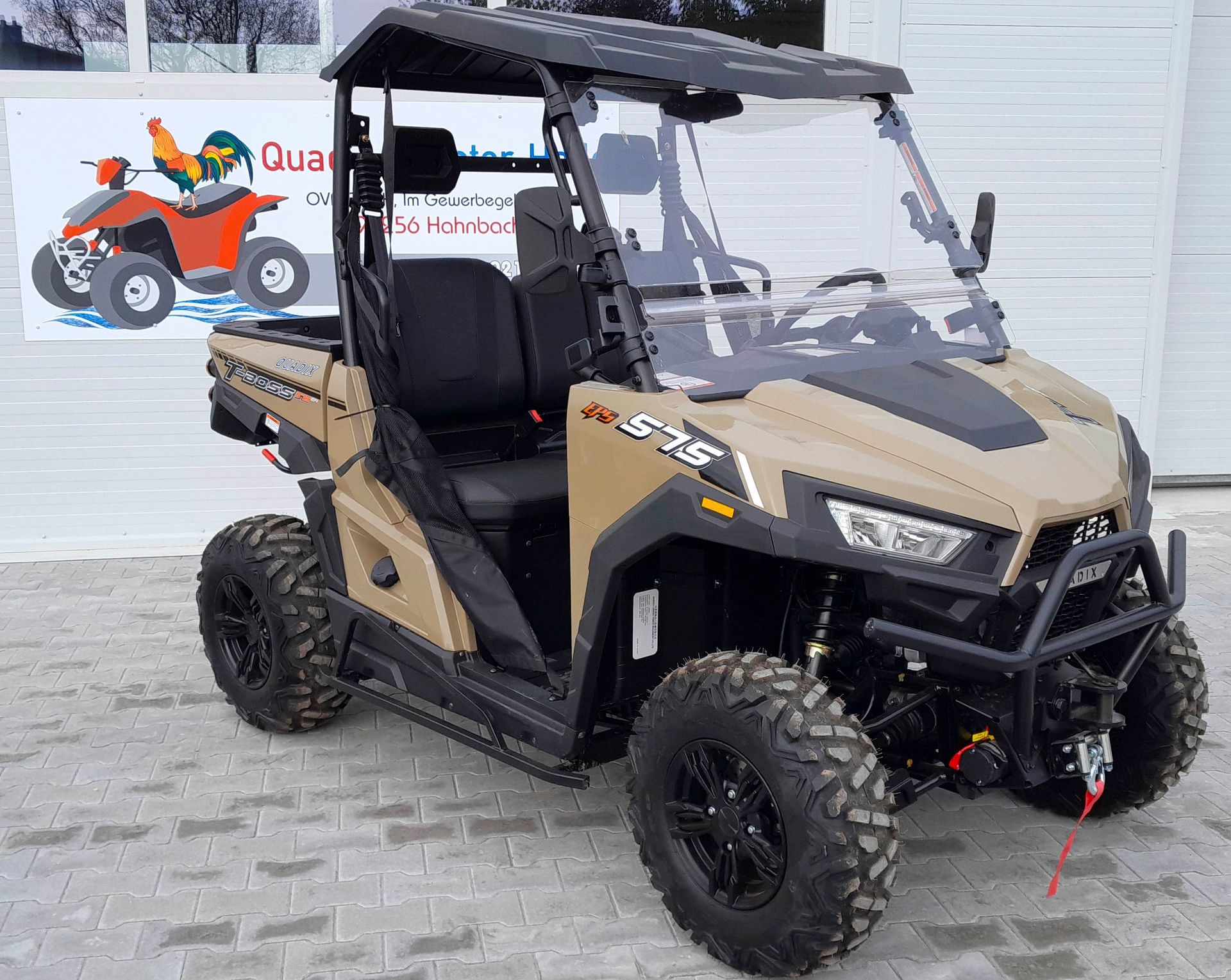 Ein braun-schwarzes Geländefahrzeug ist vor einem Garagentor geparkt.