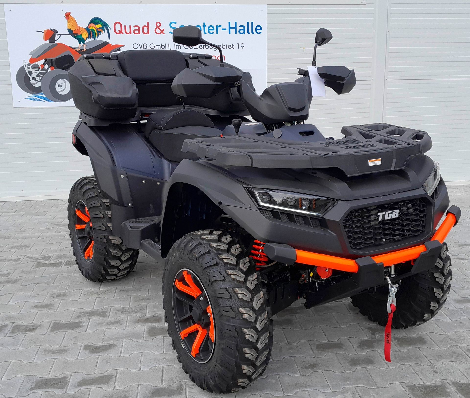 Ein schwarz-orangefarbenes Geländefahrzeug ist vor einem Gebäude geparkt.