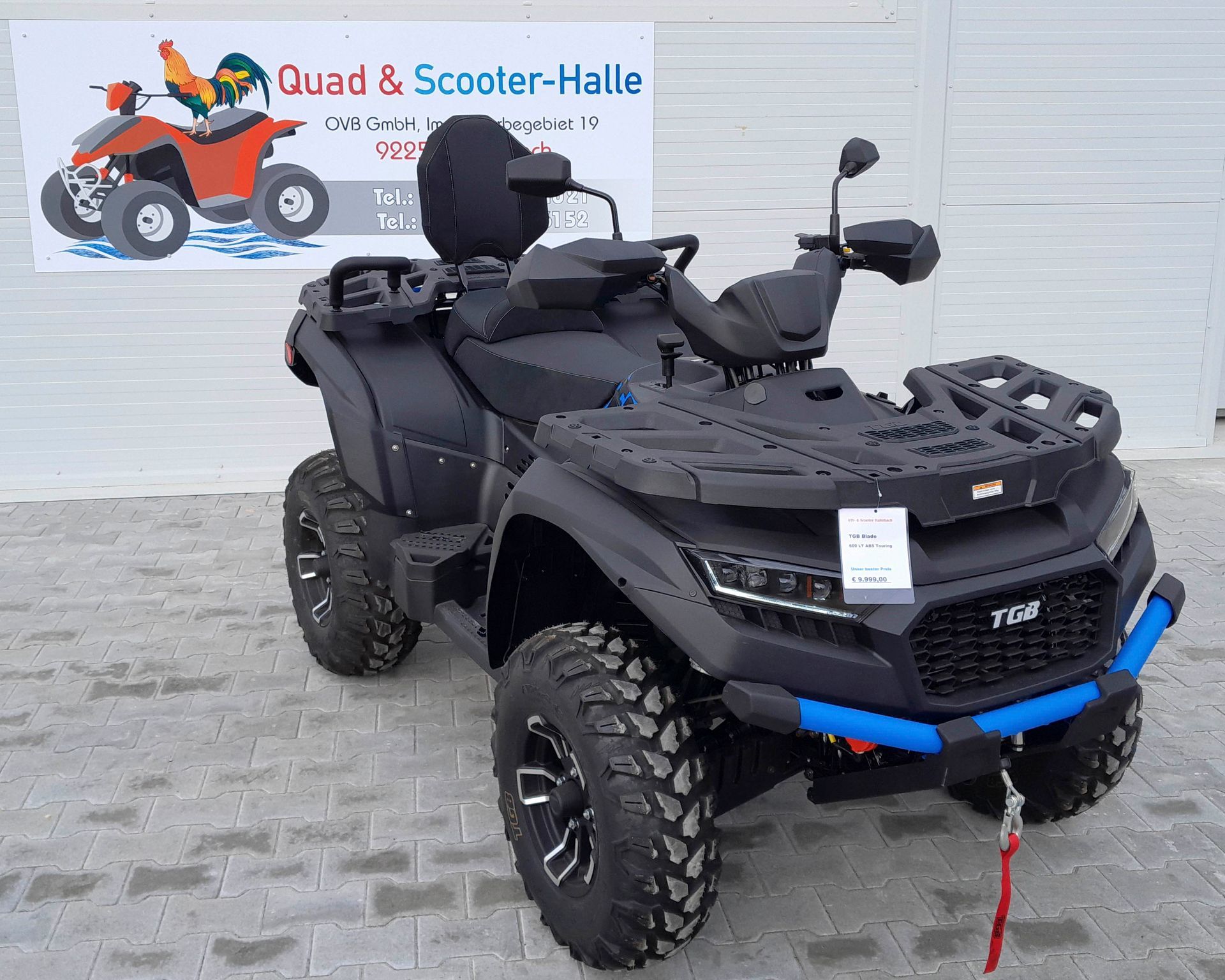 Ein schwarzes ATV parkt vor einem Schild mit der Aufschrift „Quad & Scooter-Halle“.