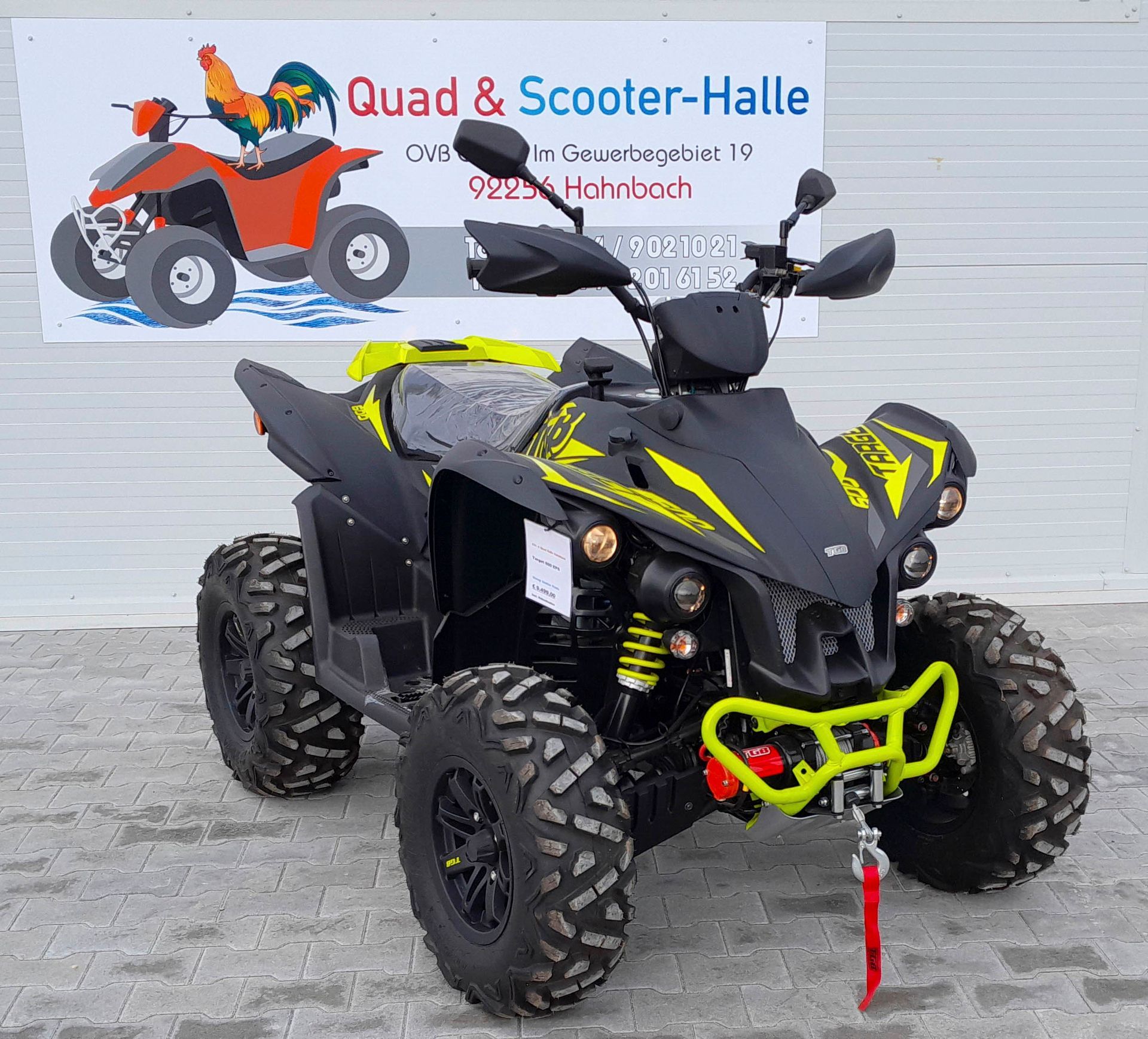 Ein schwarz-gelbes ATV parkt vor einem Schild mit der Aufschrift „Quad & Scooter-Halle“.