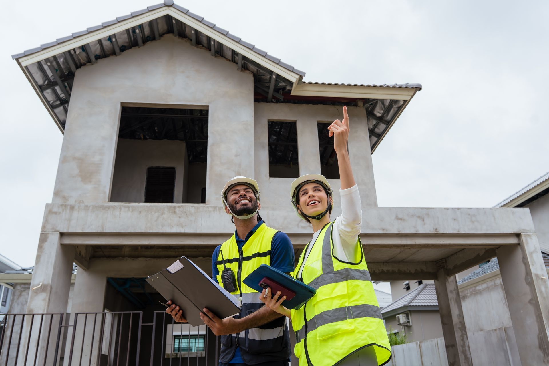 Deux ouvriers du bâtiment se tiennent devant une maison.