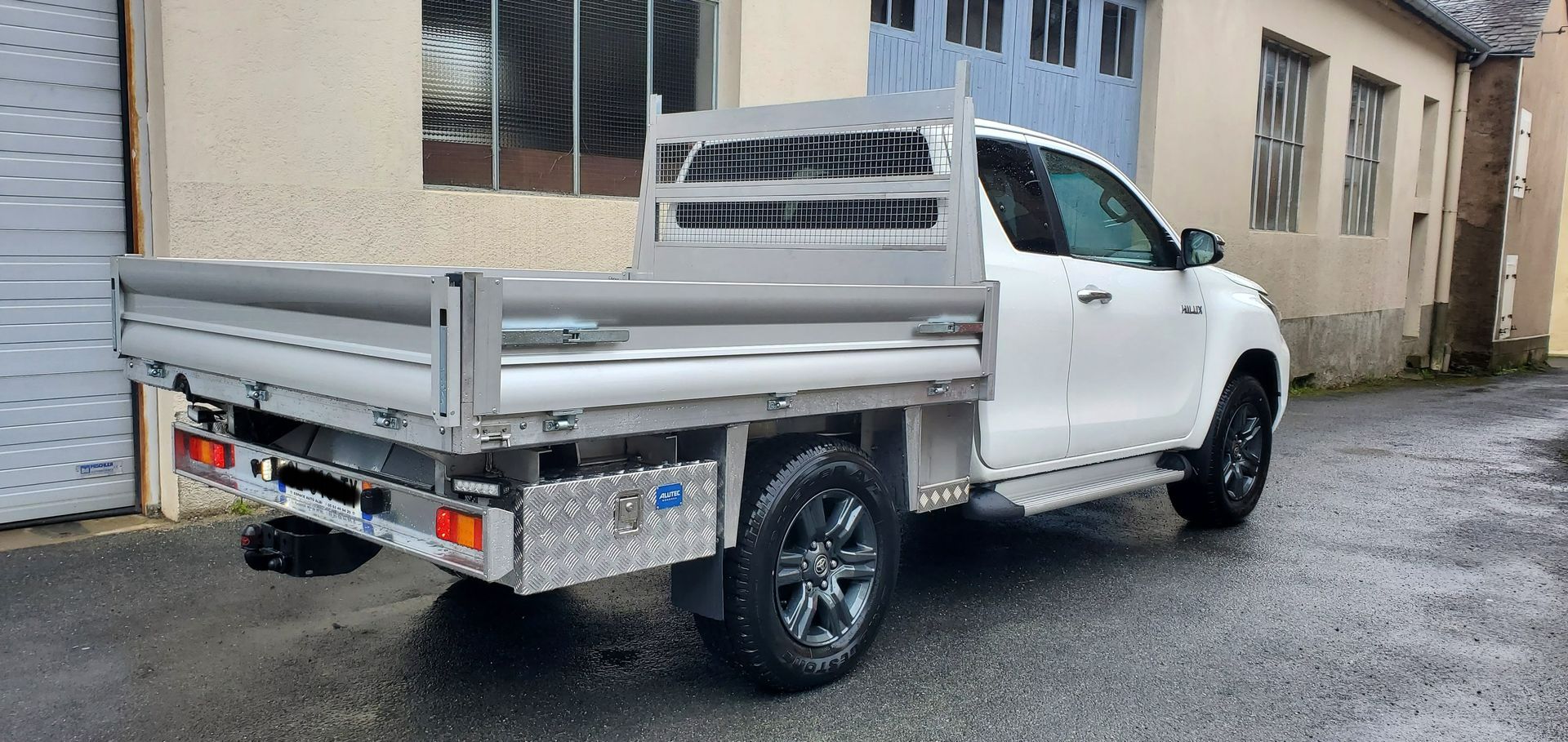 Camionnette blanche à plateau garée dans une rue.