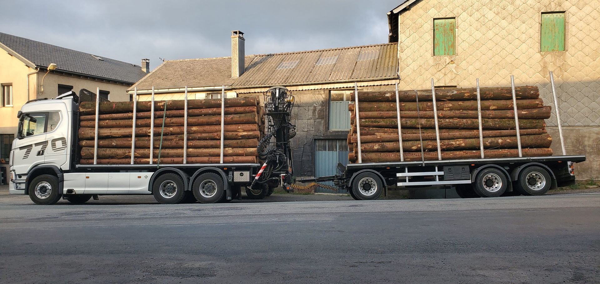 Deux camions plateaux  bois chargés de grumes empilées.
