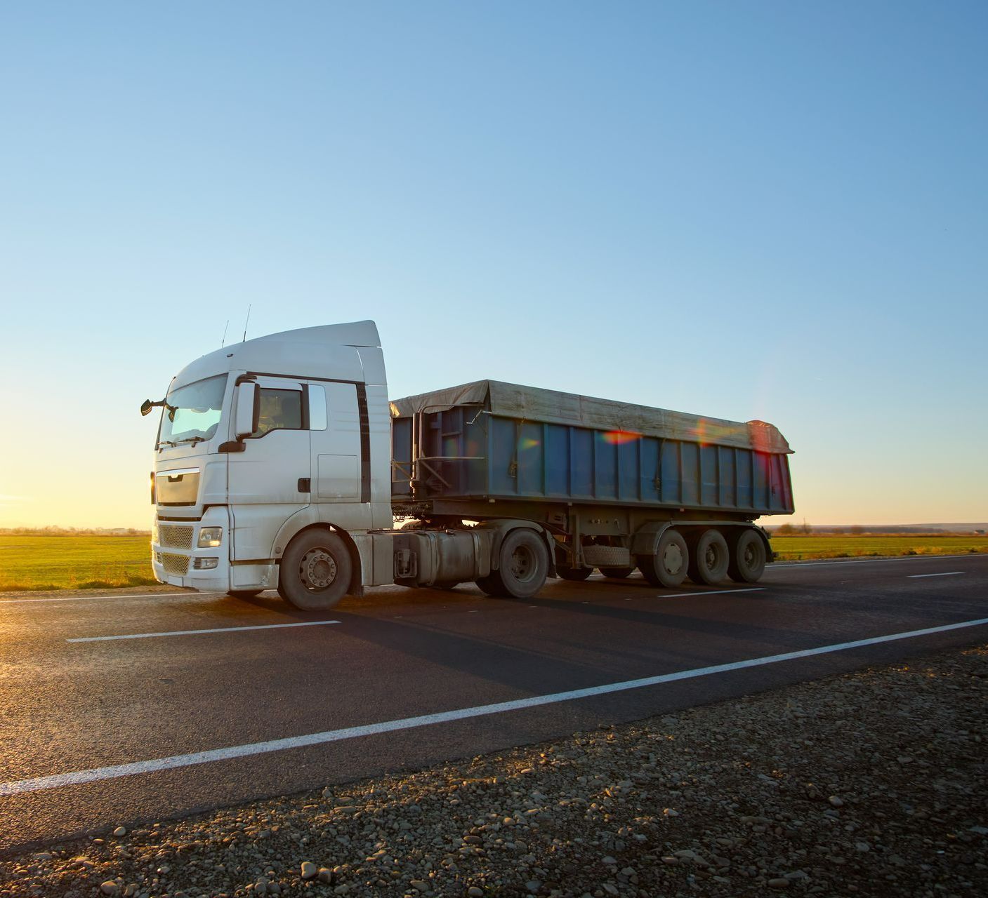 Un camion avec sa remorque bâchée sur une route