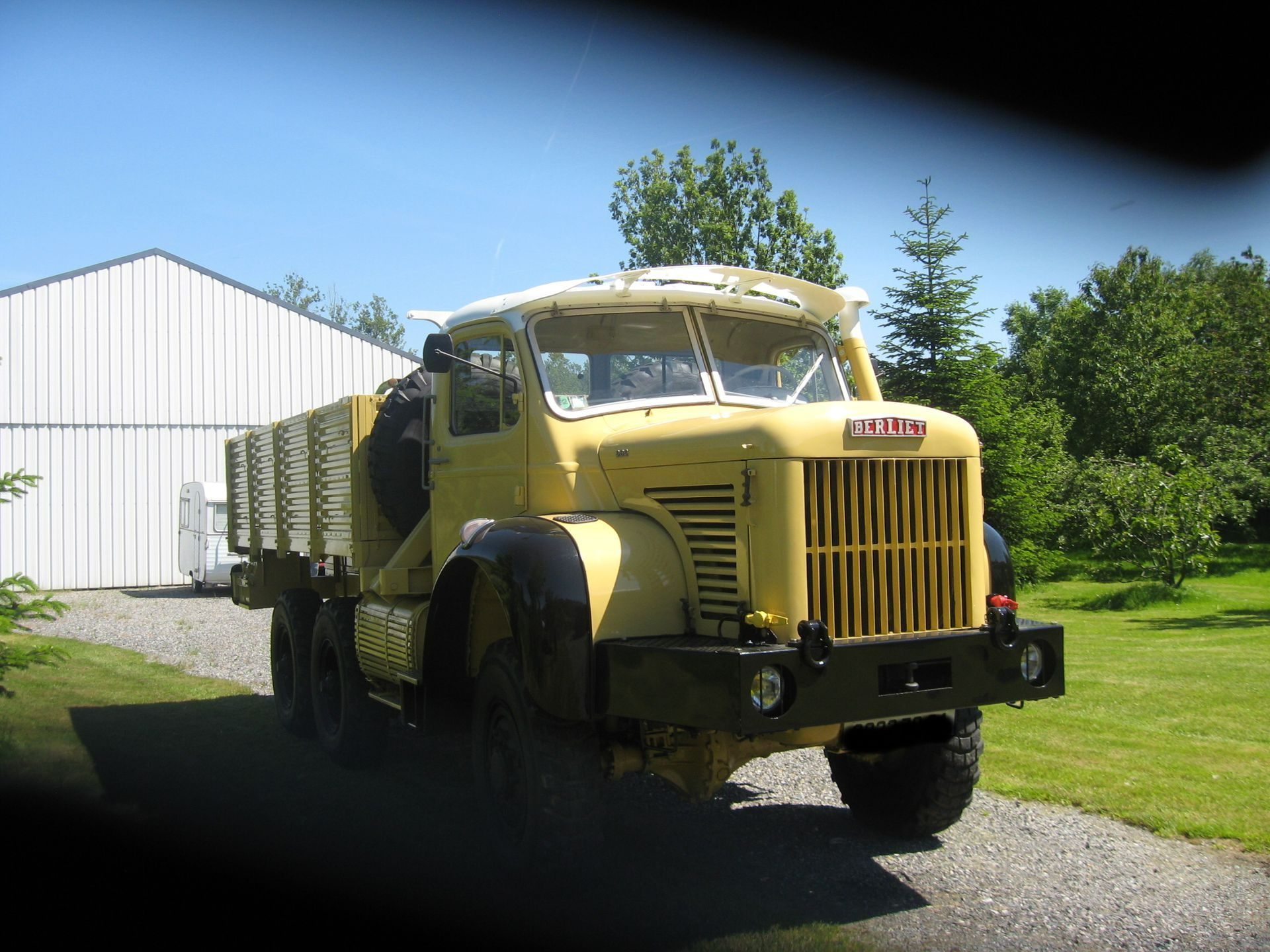 Un camion de couleur jaune devant un atelier