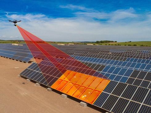 Un dron rocía niebla roja sobre paneles solares en una granja solar en el desierto.