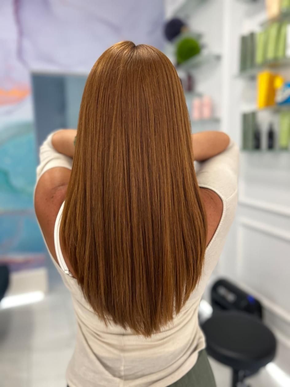 Persona con cabello largo, liso y castaño, vista de espaldas en una silla de peluquería.