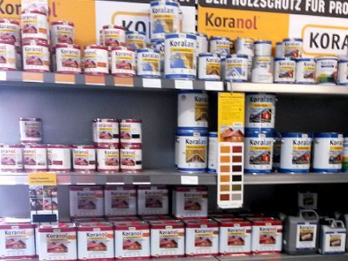 Regale mit Holzschutzfarben der Marke „Koralan“ in verschiedenen Größen in einem Baumarkt.