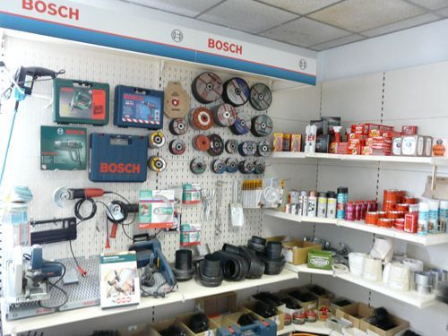 Bosch-Werkzeugdisplay: Elektrowerkzeuge, Zubehör und Verbrauchsmaterial auf Regalen und Lochwänden in einem Baumarkt.