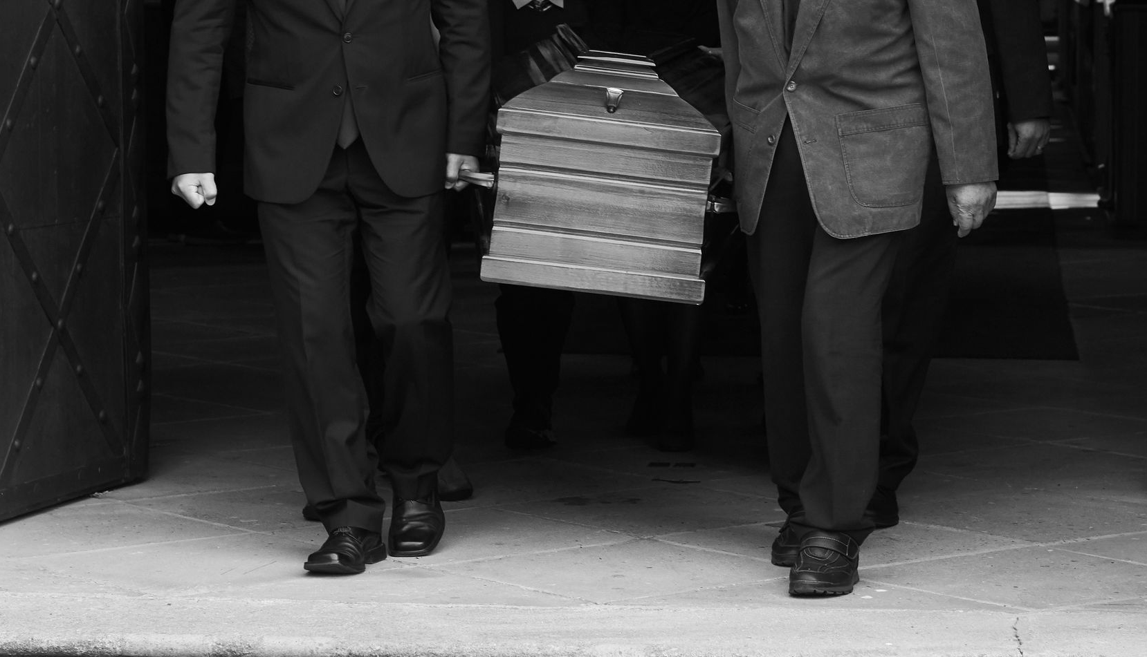 Deux hommes en costume transportant un paquet empilé à travers l'entrée d'un bâtiment