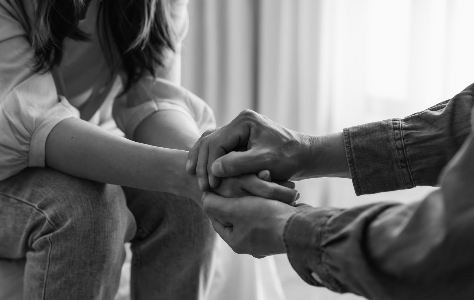 Deux personnes se tiennent la main lors d'une conversation dans une pièce à la lumière tamisée