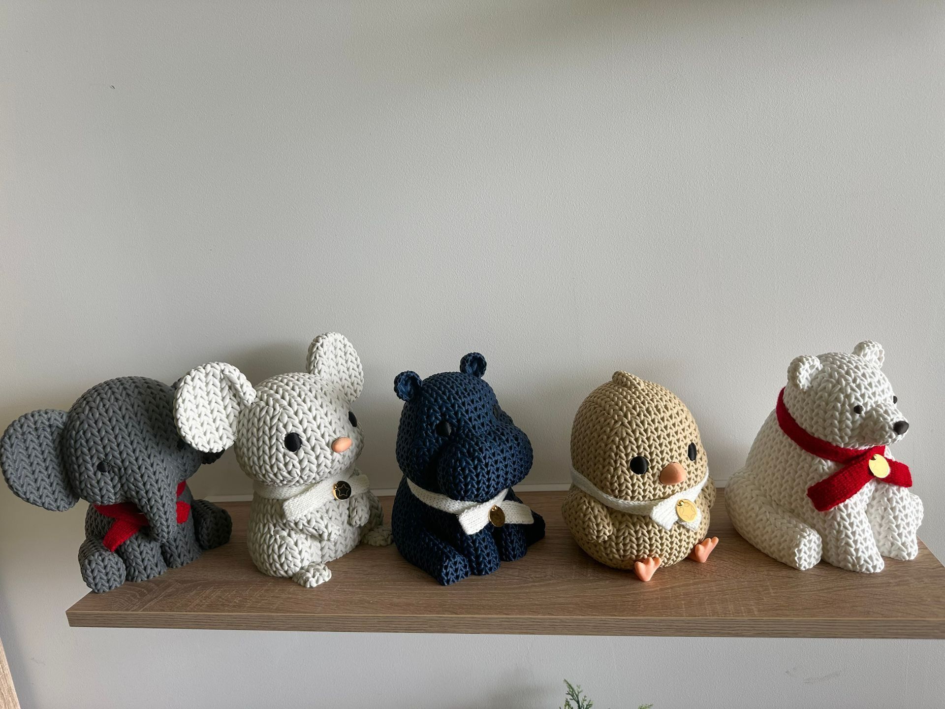Cinq animaux crochetés — un éléphant, une souris, un hippopotame, un poussin et un ours — posés sur une étagère en bois