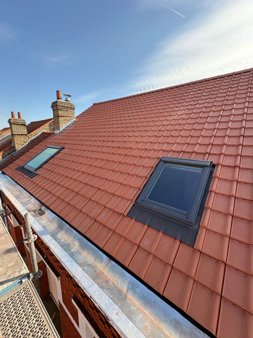 Toiture en construction avec un système de gouttières et une section de tuiles.