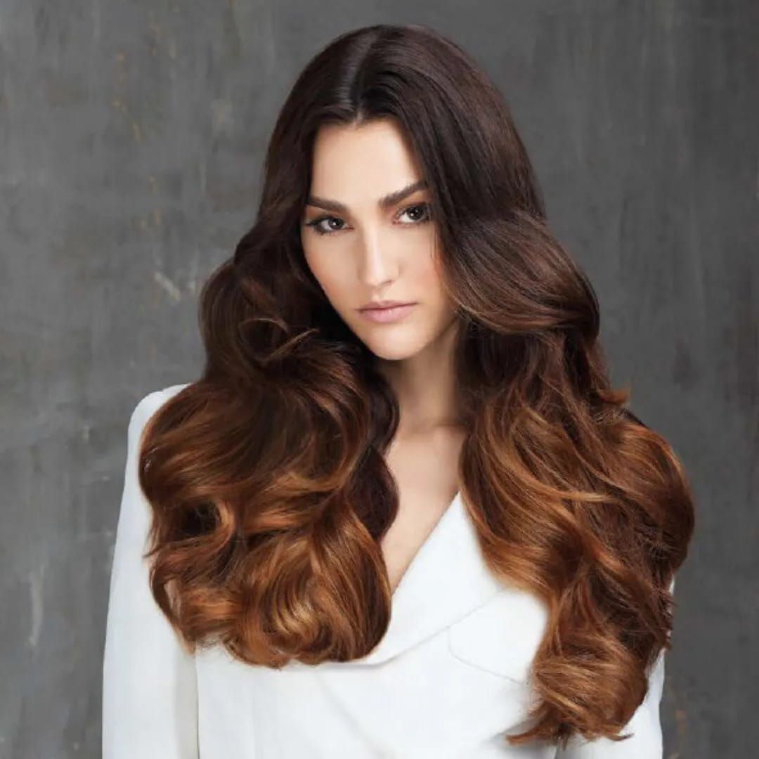 Un barbero le corta el pelo a un hombre en una barbería. El hombre tiene barba, y el barbero usa tijeras y peine.