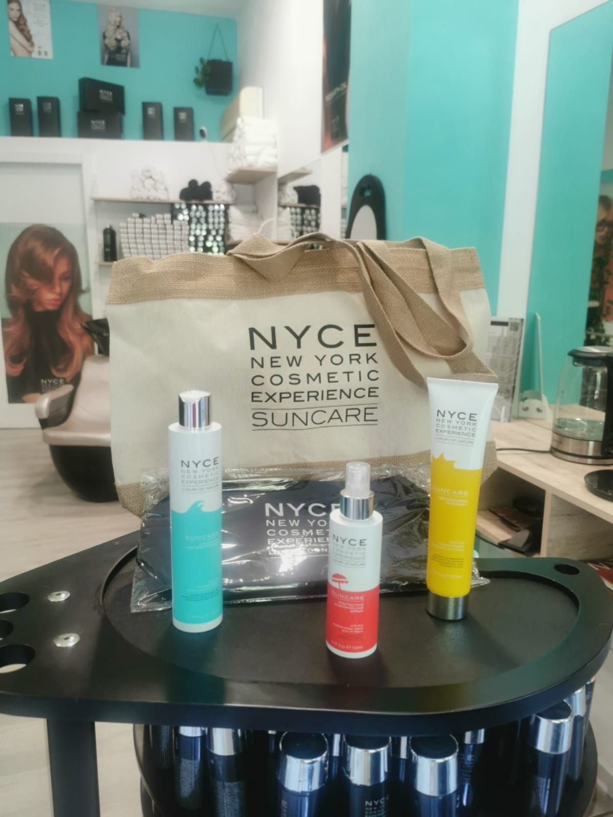 Exhibición de productos cosméticos de la marca NYCE en un salón. Una bolsa grande y varios frascos.