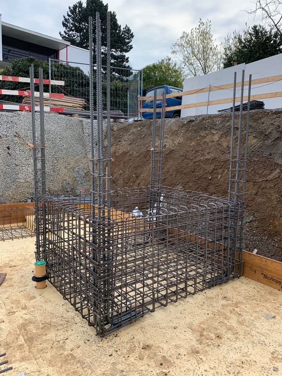 Stahlbetonrahmen für eine Betonkonstruktion im Bau auf einem planierten, unbefestigten Gelände.