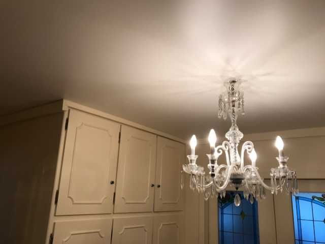 Pièce blanche avec placards intégrés et un lustre suspendu près des vitres bleues.
