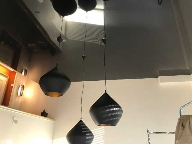 Suspensions noires avec abat-jour coniques et en forme de larme dans une pièce moderne avec un haut plafond