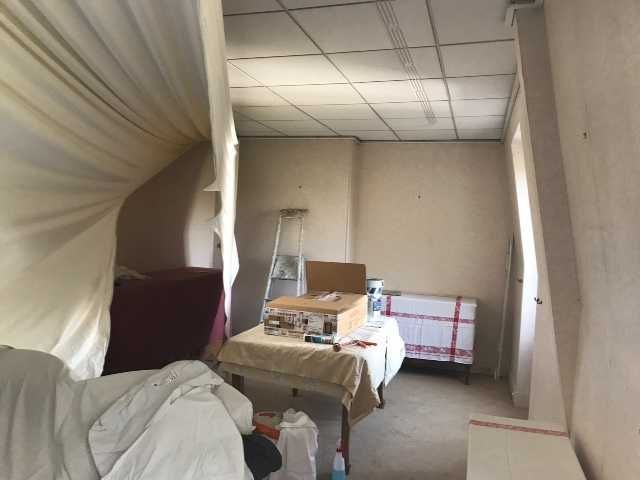 Petite pièce avec des meubles recouverts de housses, une échelle et des cartons en cours de rénovation ou de stockage.