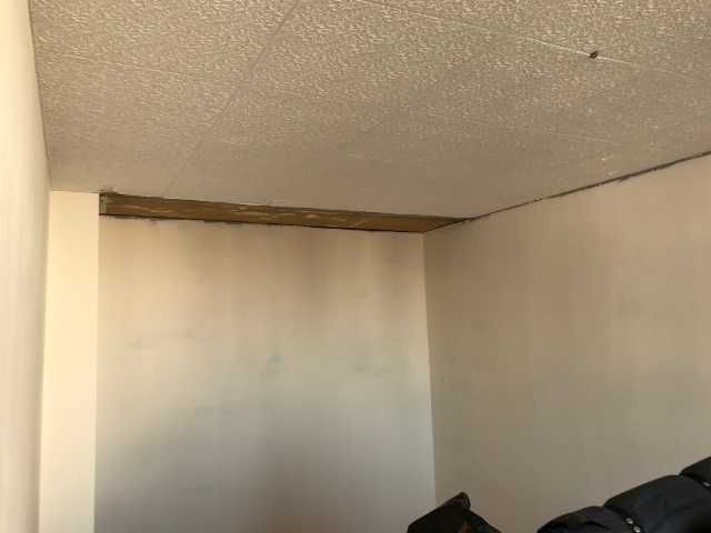 Plafond de chambre endommagé avec une longue fissure ouverte près du mur