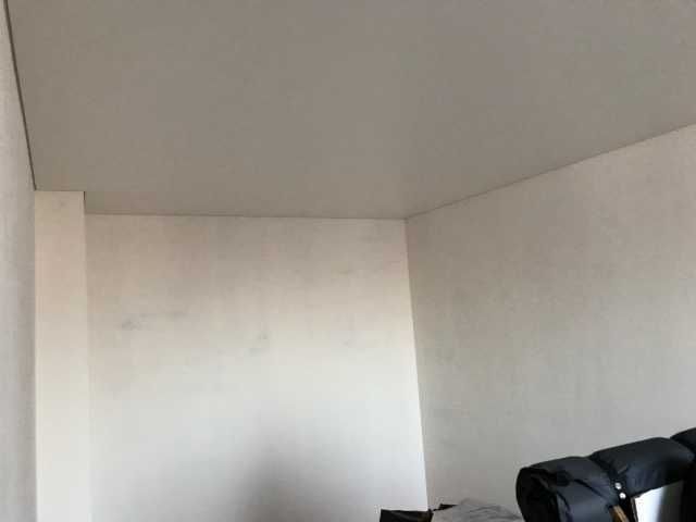 Coin blanc nu d'une pièce avec une chaise noire au premier plan, en bas à droite.