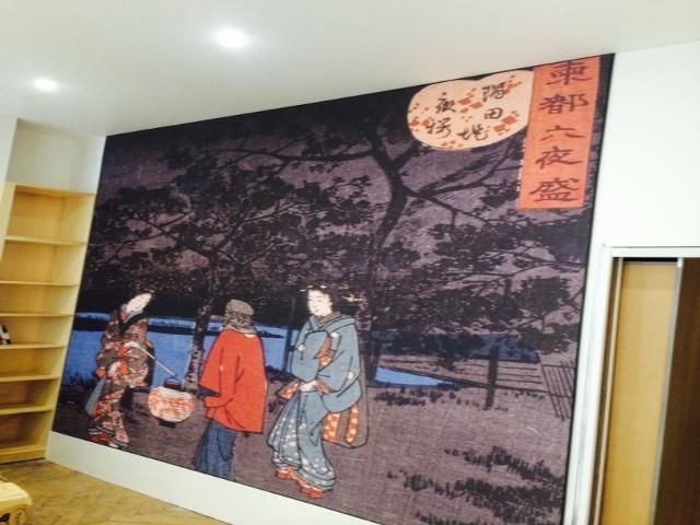 Estampe japonaise sur bois représentant trois personnages en kimono sous des cerisiers en fleurs dans une pièce
