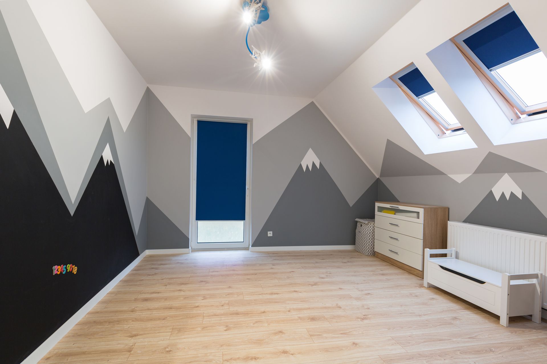 Pièce moderne vide avec des murs gris, un parquet clair, une porte bleue, des puits de lumière et un banc blanc.