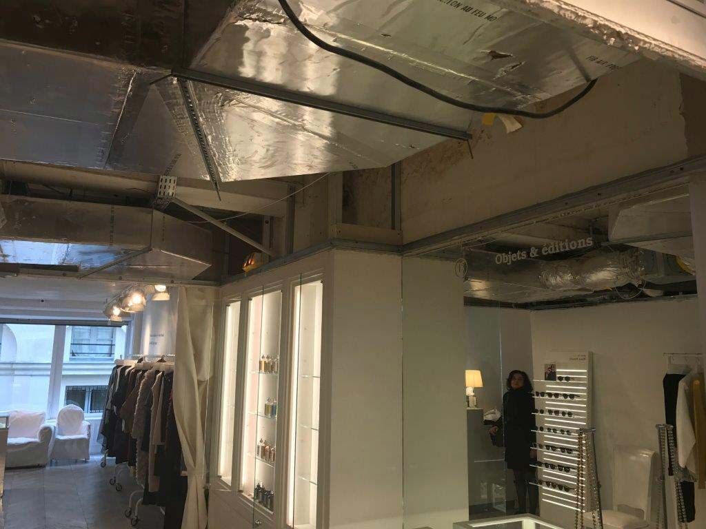 Intérieur de bureau moderne avec conduits apparents, murs blancs, portants à vêtements près d'une fenêtre.
