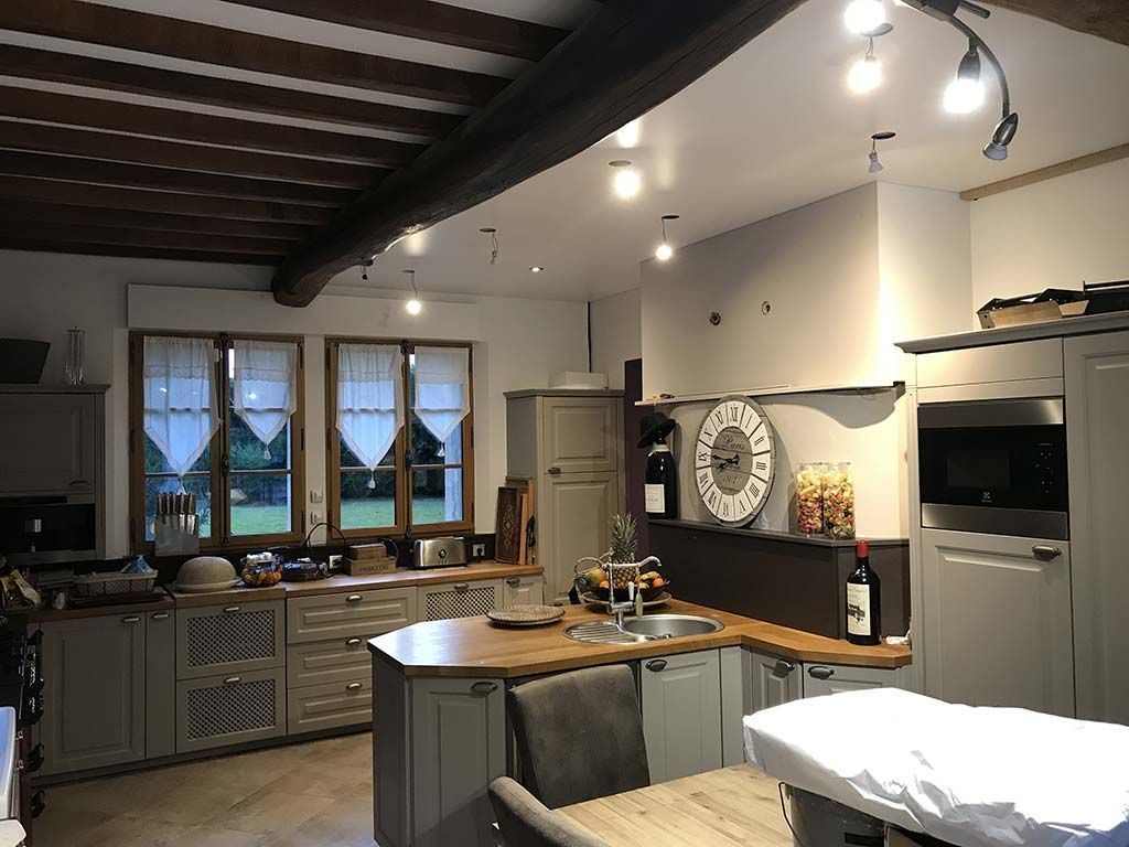 Cuisine moderne avec poutres apparentes, îlot central, placards et fenêtre au-dessus de l'évier