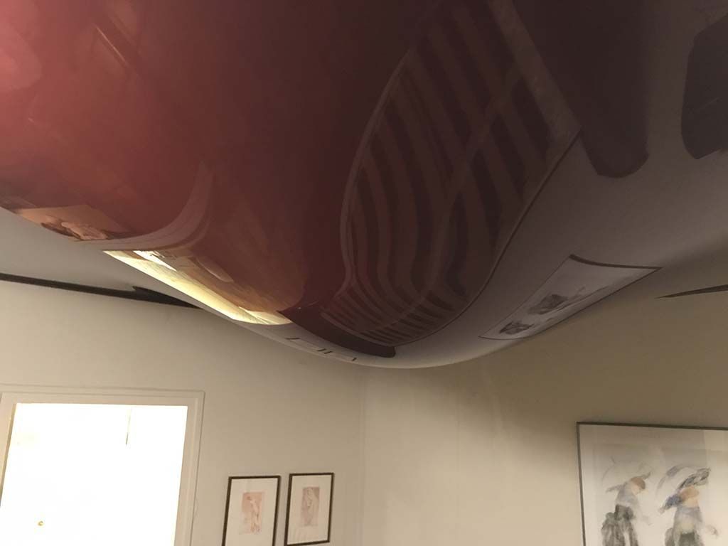 Grand objet rayé suspendu près du plafond dans une pièce ornée de tableaux encadrés et de fenêtres