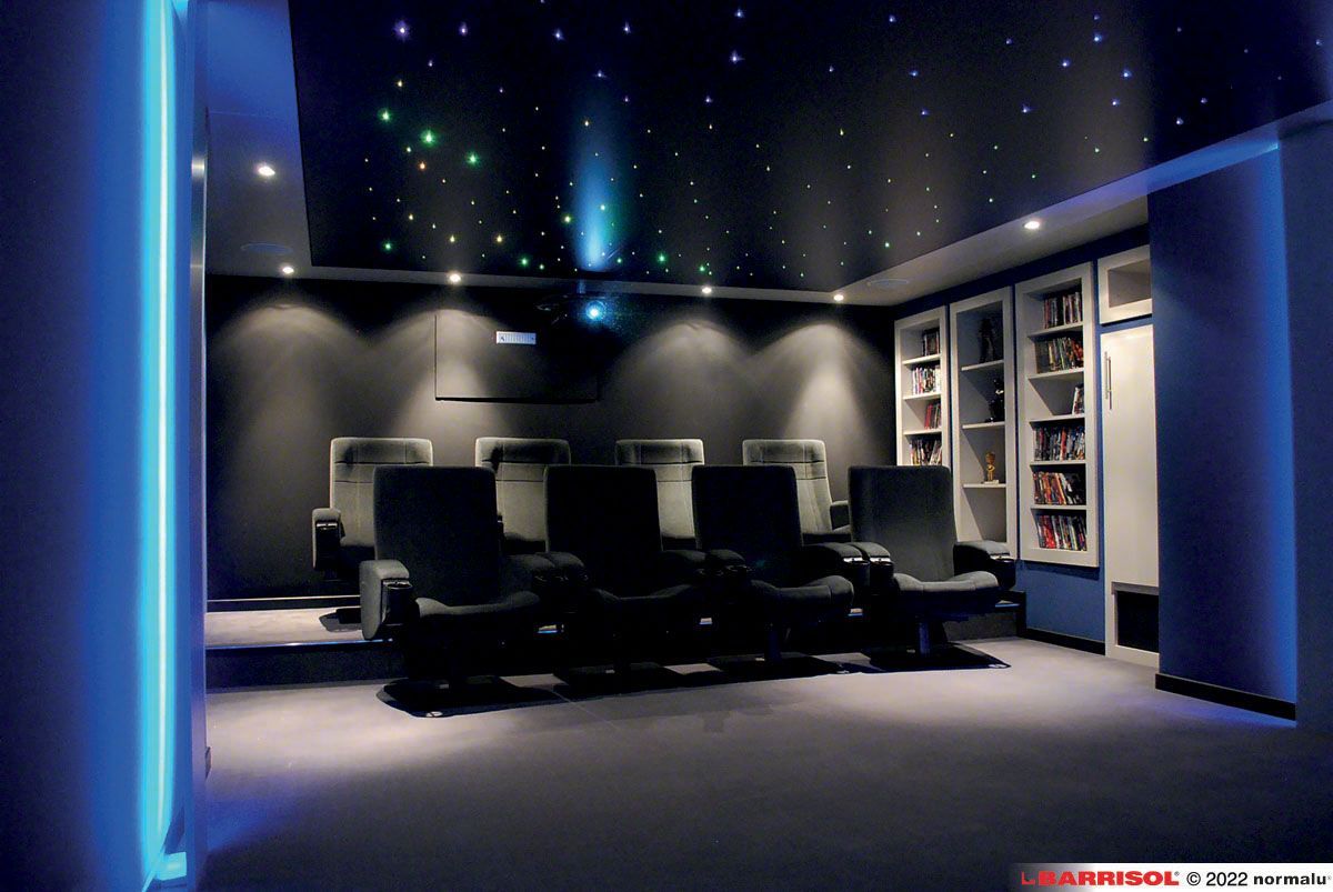 Salle de cinéma maison moderne et sombre avec trois fauteuils inclinables, éclairage d'ambiance bleu et plafond étoilé