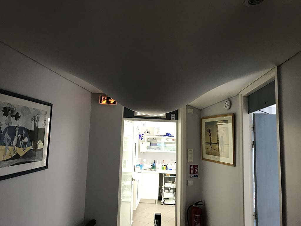 Un couloir étroit mène à une cuisine lumineuse, avec des tableaux encadrés aux murs et un plafond incurvé.