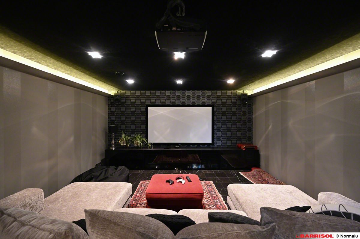 Salle de cinéma maison moderne avec écran de projection, plafond noir et fauteuils gris.