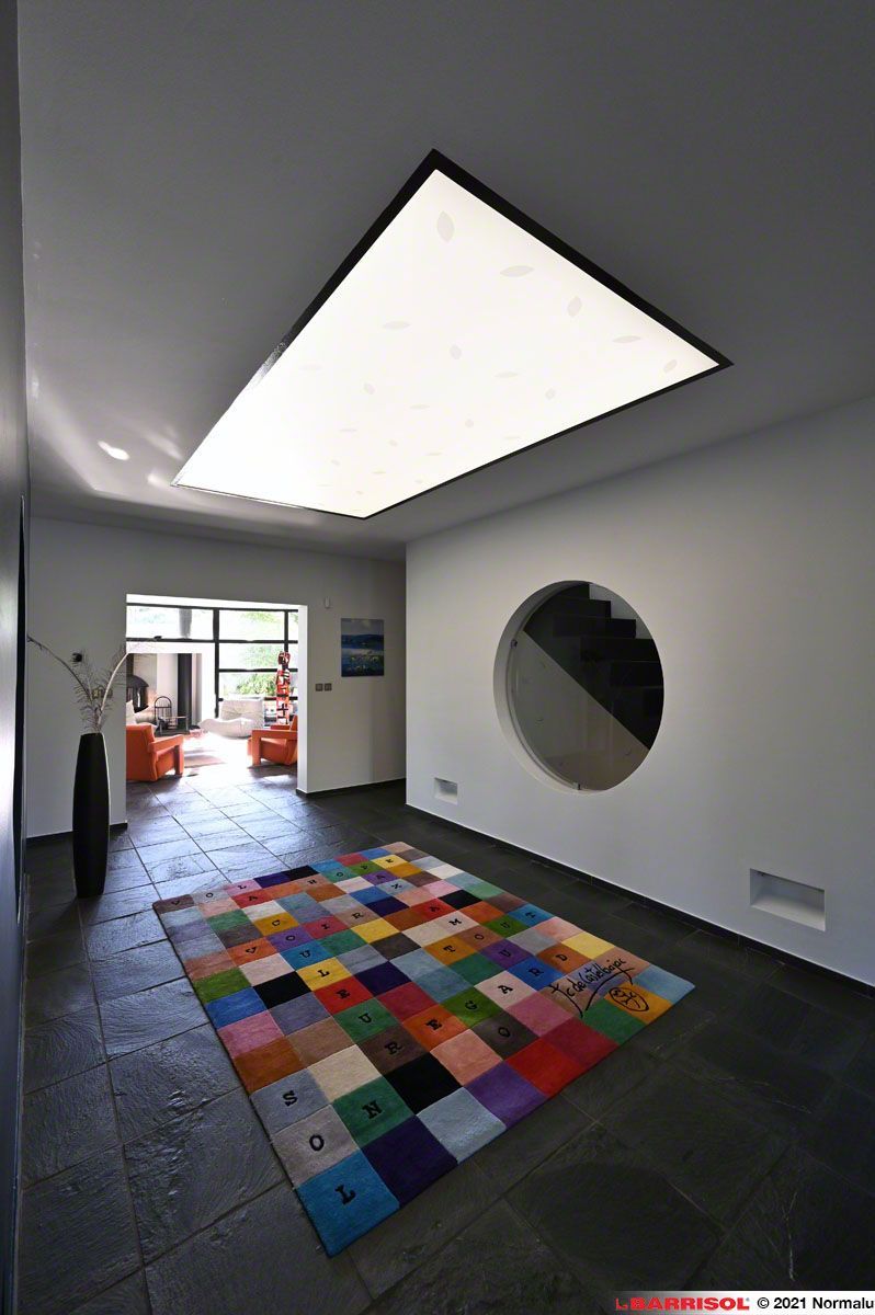 Chambre moderne avec une grande verrière, une fenêtre murale circulaire et un tapis patchwork coloré