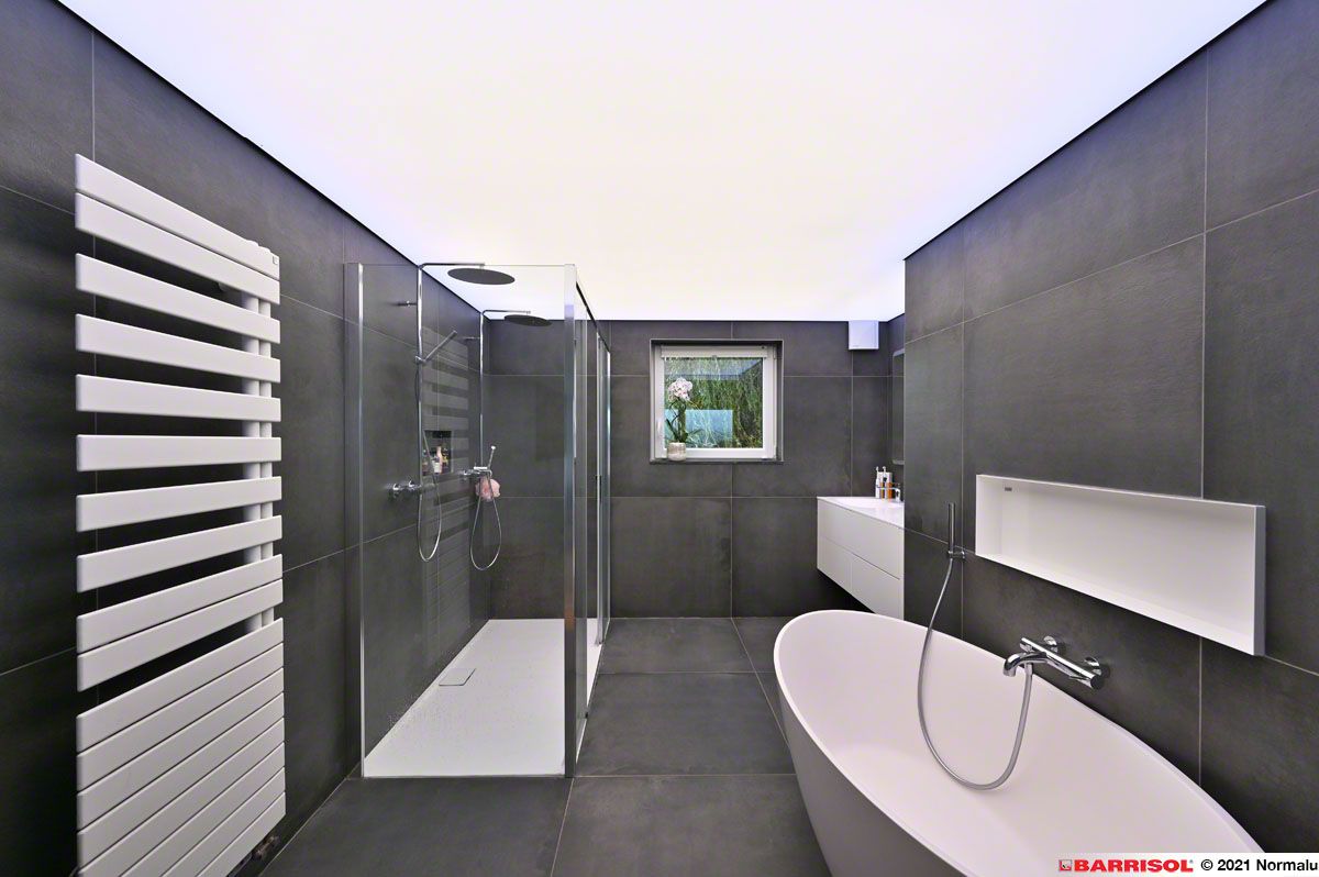 Salle de bains moderne avec carrelage foncé, douche en verre, radiateur mural et baignoire îlot.