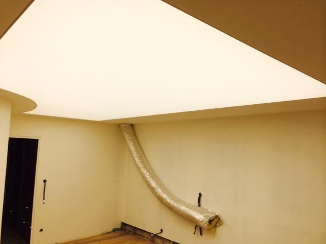 Pièce endommagée avec un plafond affaissé et un conduit ou un tuyau qui pend le long du mur.