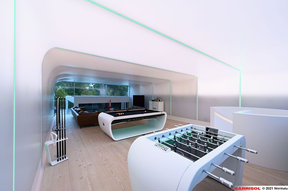 Intérieur moderne et ouvert avec des bureaux blancs épurés, du parquet et un coin salon sous un éclairage tamisé.