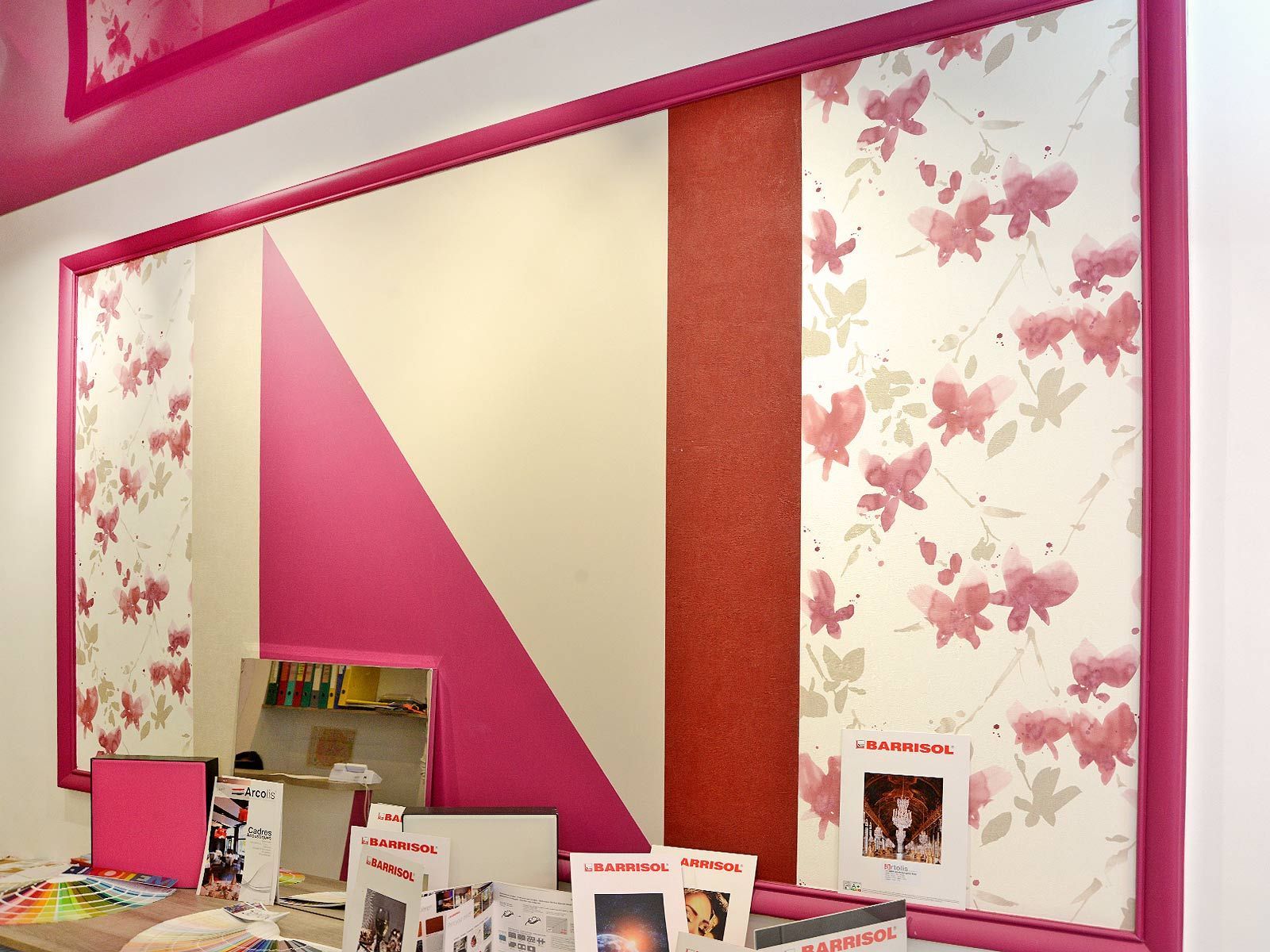 Mur d'exposition floral rose et crème avec panneau géométrique et magazines sur comptoir