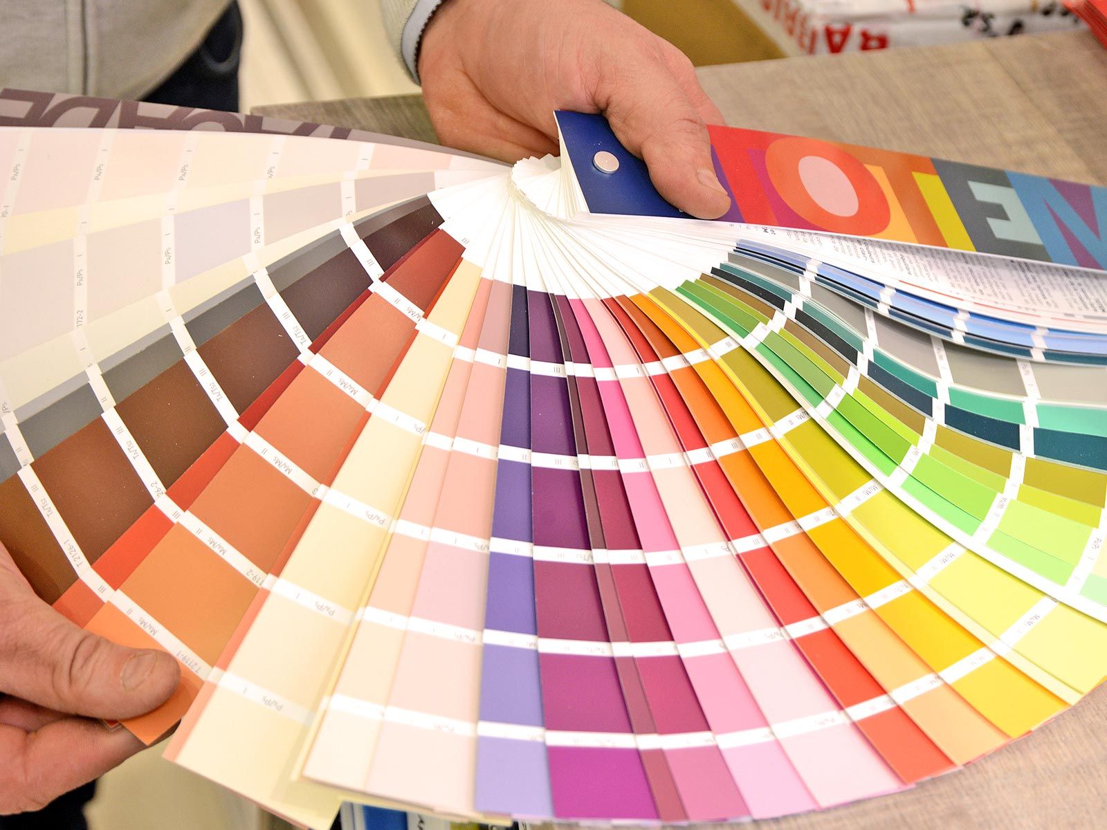 Des mains déploient des échantillons de peinture colorée avec une palette arc-en-ciel.