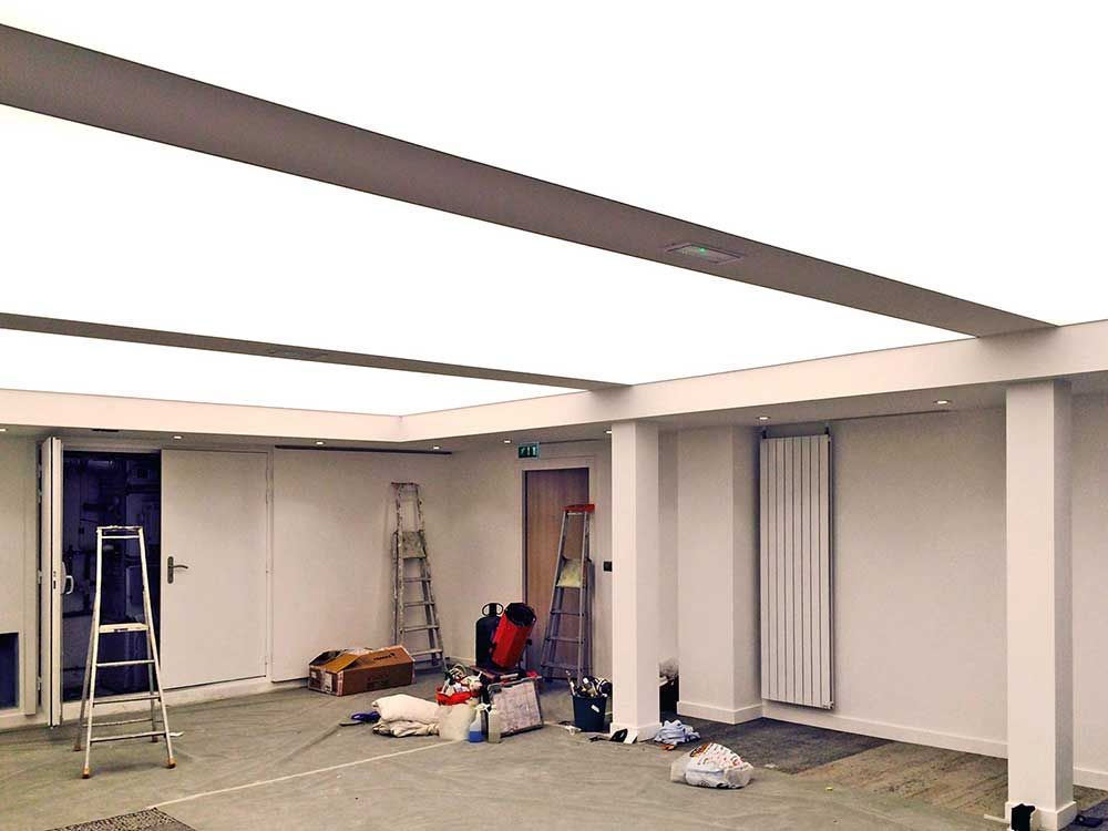Pièce vide en cours de rénovation avec une échelle, des outils et des fournitures éparpillés au sol
