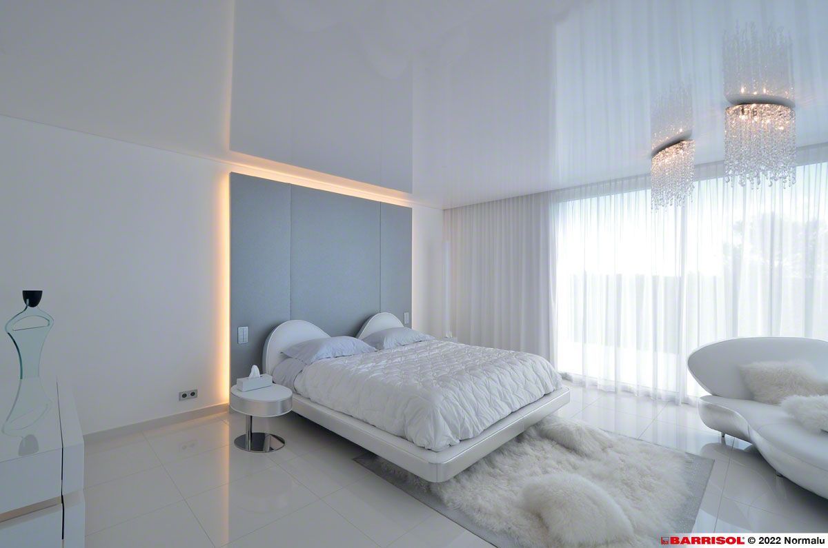 Chambre moderne blanche avec un grand lit, des voilages, un sol brillant et un éclairage d'ambiance doux.