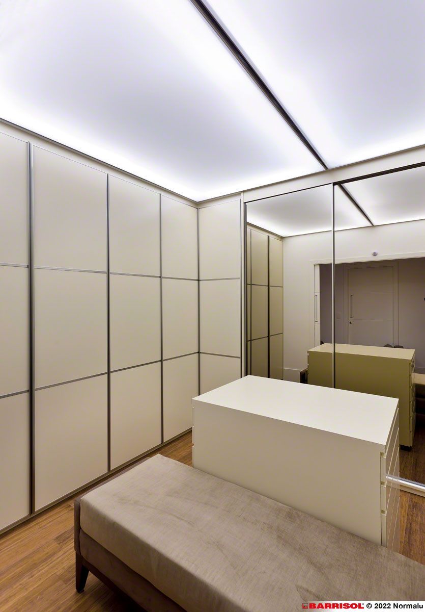 Chambre moderne avec panneaux beiges, un lit et des portes de placard à miroir