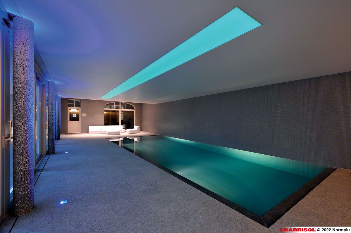 Piscine intérieure moderne avec eau éclairée en bleu et design minimaliste et élégant