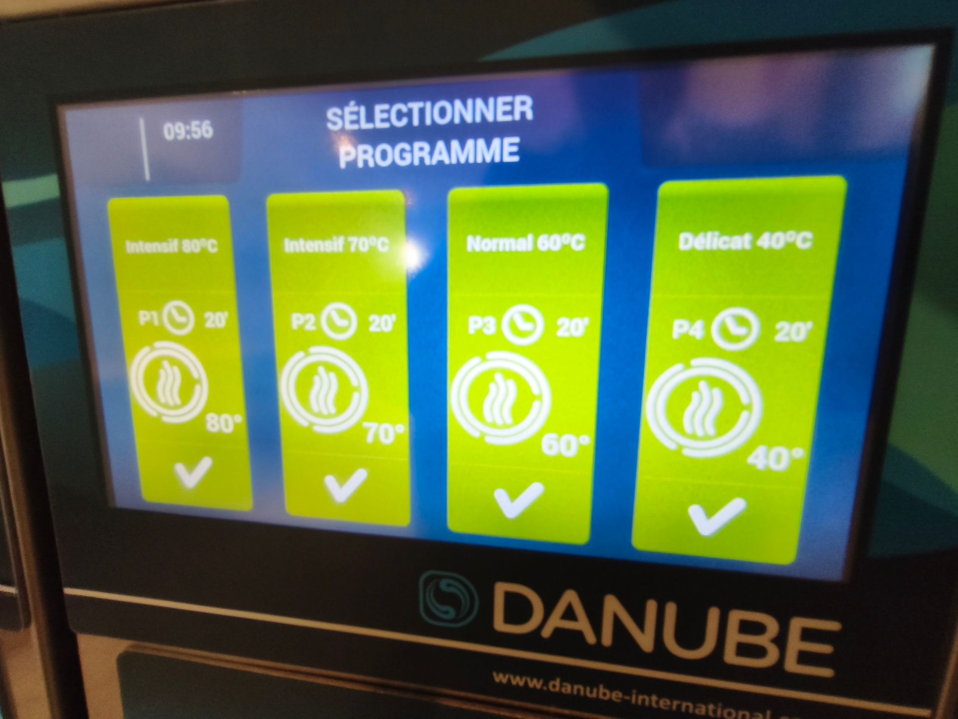 Laverie en libre-service avec des lave-linge et des sèche-linge à chargement frontal superposés, contre un mur carrelé