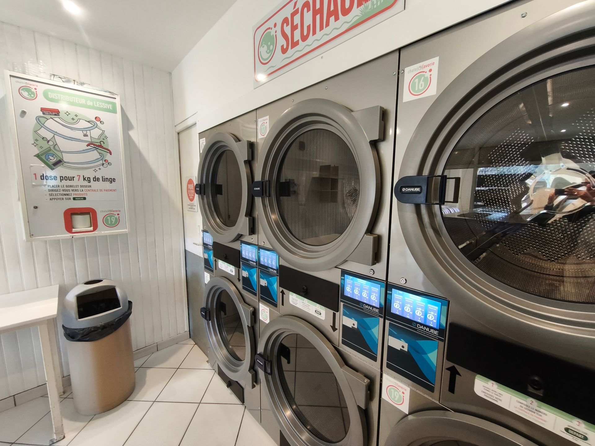 Buanderie avec lave-linge et sèche-linge superposés, ainsi que des plans de pliage et des terminaux de paiement