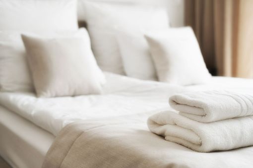Lit blanc avec des serviettes soigneusement pliées dans une chambre d'hôtel.